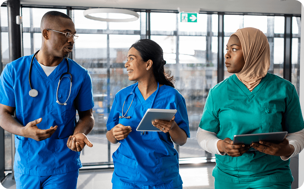 Three people in medical scrubs walking and talking.